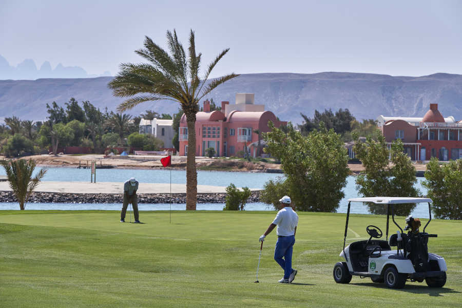 Tee time at Steigenberger Golf Resort in El Gouna with Red Sea lagoon view, golf car and two men