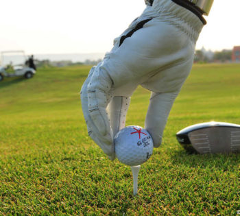 A man is wearing golf gloves and holding the golf ball in El Gouna Red Sea Golf