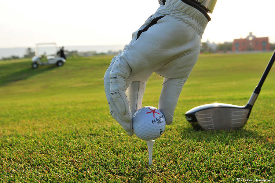 A man is wearing golf gloves and holding the golf ball in El Gouna Red Sea Golf