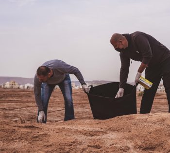 two men cleaning up garbage beach desert el gouna during earth week