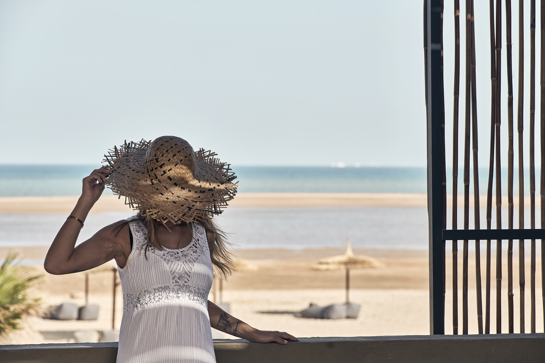 A girl wearing sun hat in the balcony with a sea view.