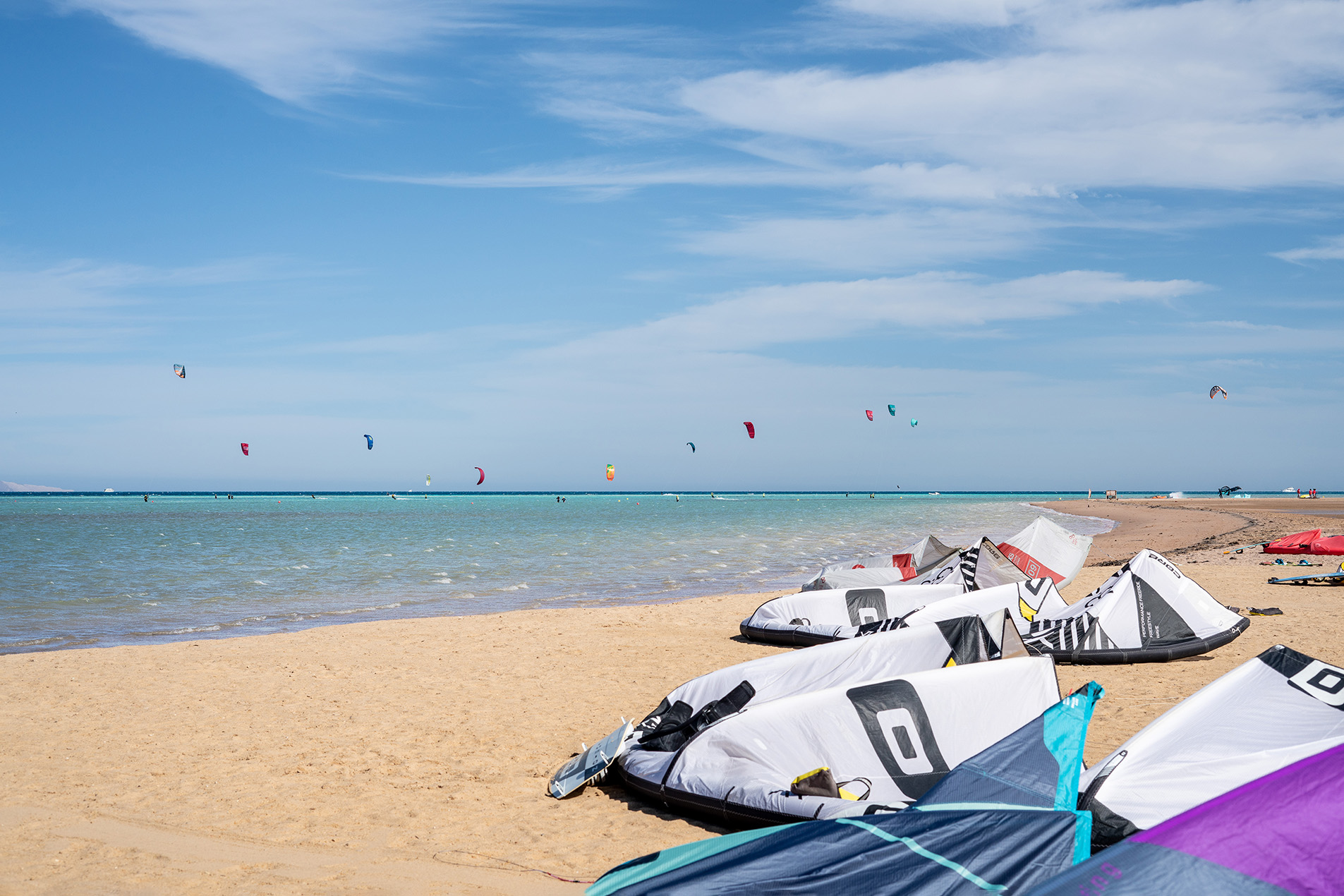 Photo for a sandy beach and people kite surfing and kites prepared to use.