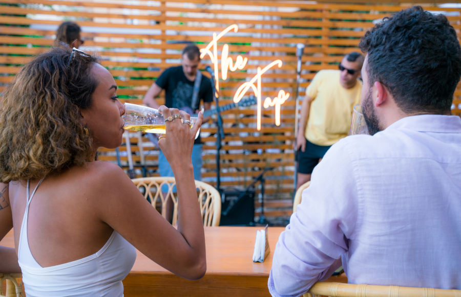 a man and a woman drinking beer, watching music perfomance at the tap